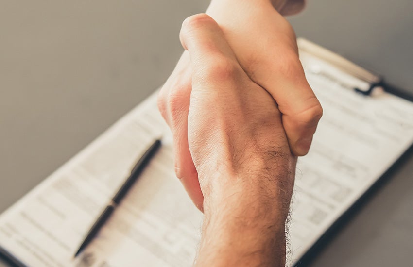 Customer reviewing used SUV financing options and shaking hands